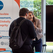 Attendees speaking beside an exhibition stand.