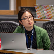 Conference attendee working on a laptop while listening to a session.