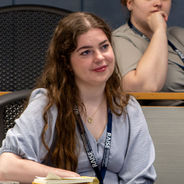 Conference attendee seated with a notebook while listening to a workshop discussion.