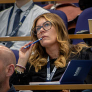 Conference attendee taking notes and listening to a presentation.
