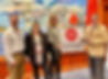 Two women and a man standing in front of a sign reading MDA Michigan Downtown Association smiling.