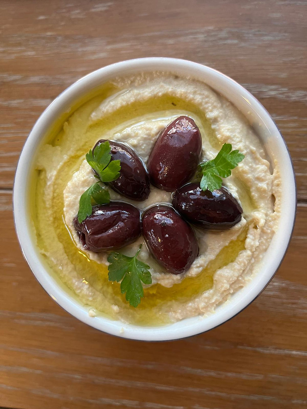 hummus topped with olive oil, kalamata olives, and parsley