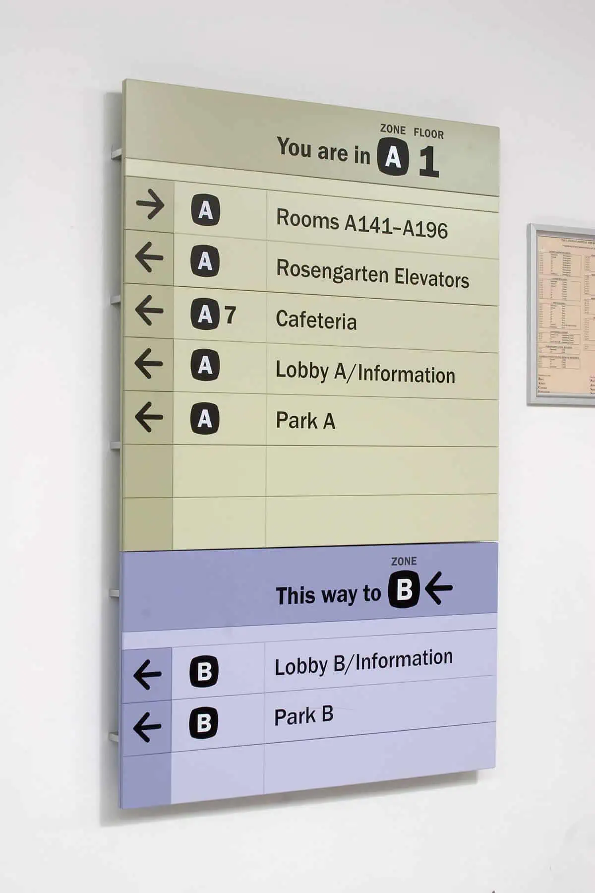 A directory sign installed on a wall showing directions to different room and areas.webp