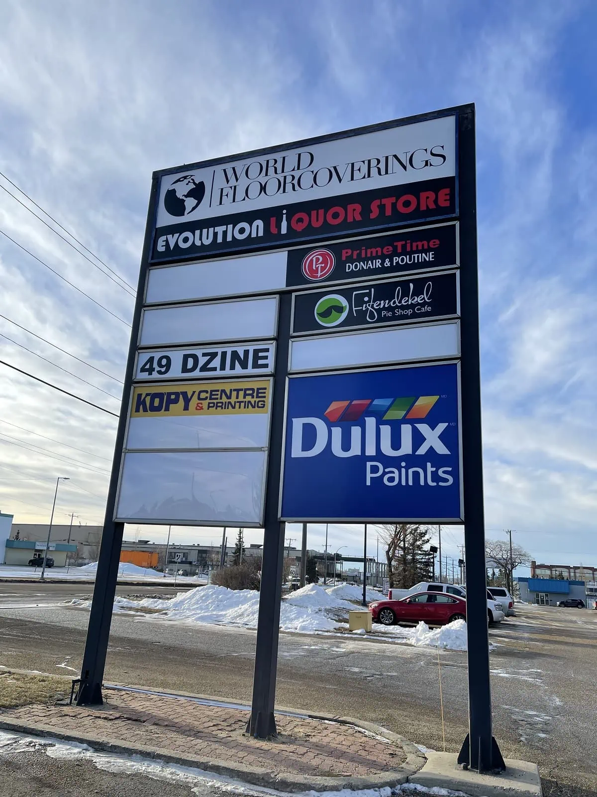 A streetside pylon sign anchored into the ground on 3 posts with business signs on it.webp