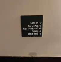Interior wayfinding sign inside a hotel's hallway that directs people to the different amenities available