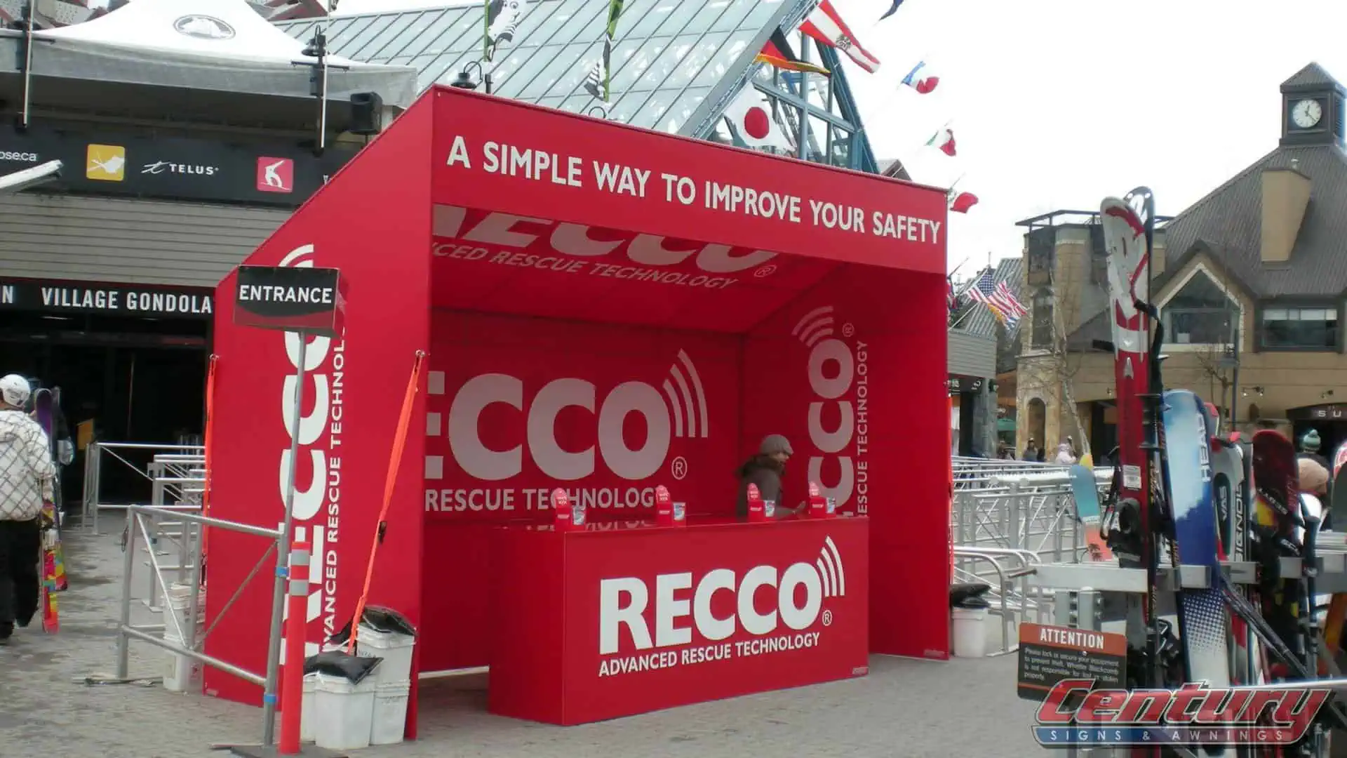 A custom red tent with branded graphics on it along with a table that has a printed table