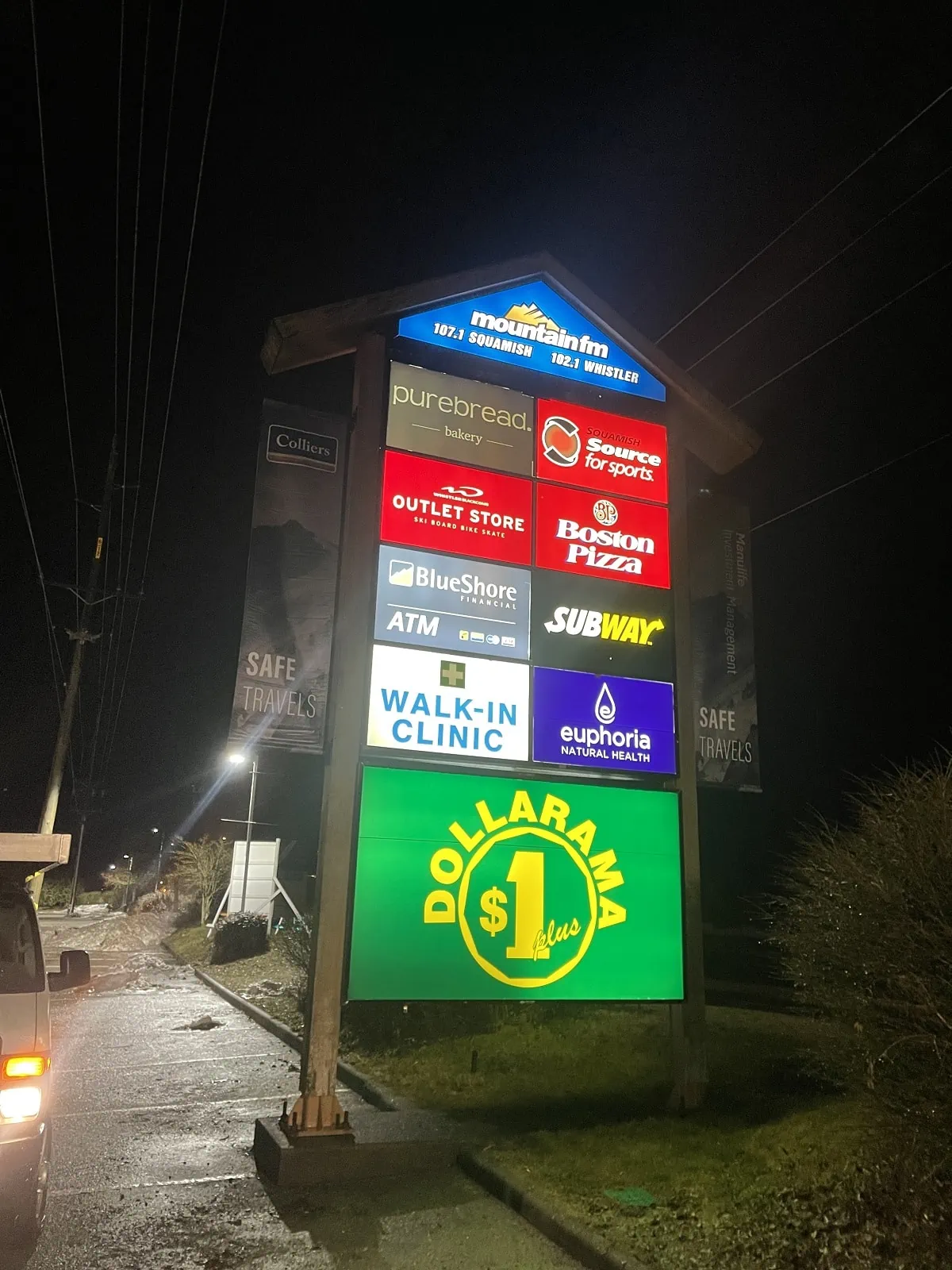 illuminated pylon sign on a sidewalk with various business logos on it.webp