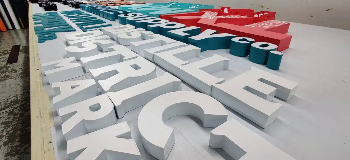 A bunch of Dimensional Letters spread out on top of a table inside a sign shop.webp