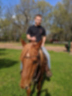 Randall is sitting astride his horse.