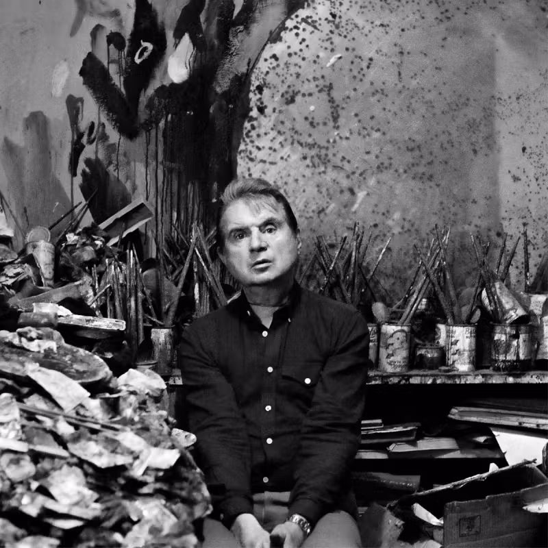 Black-and-white portrait of artist Francis Bacon, looking directly at the camera with a solemn expression