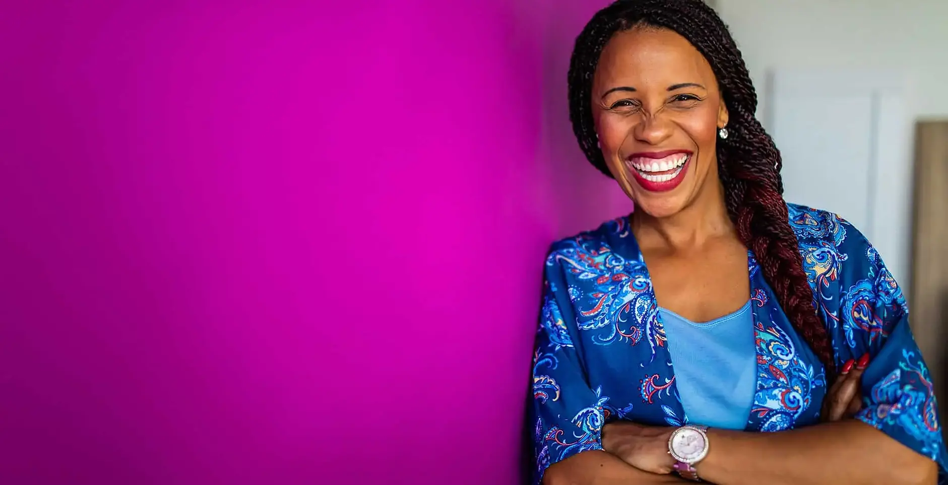 Women_Smiling_leaning_against_a_pink_wall.webp