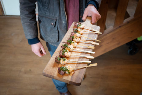 Wooden board of tasty-looking skewered meat party snacks.