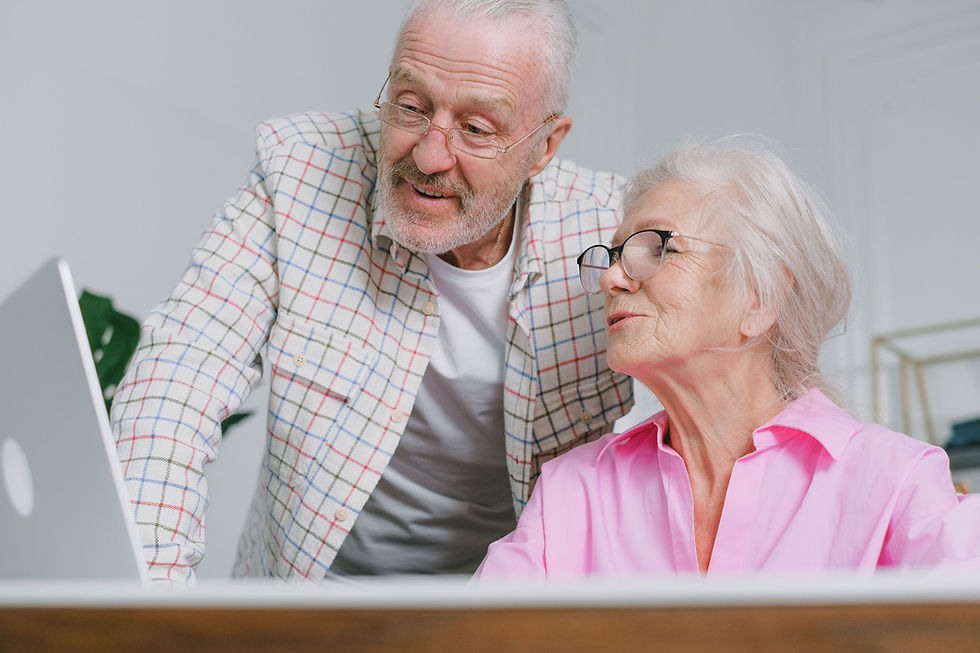 an elderly couple with eyeglasses conversing at the laptop
