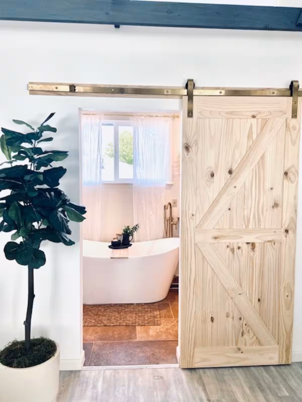 A stylish bathroom with a wooden barn door, bright natural light, and neutral tones, perfect for intimate and serene boudoir shots