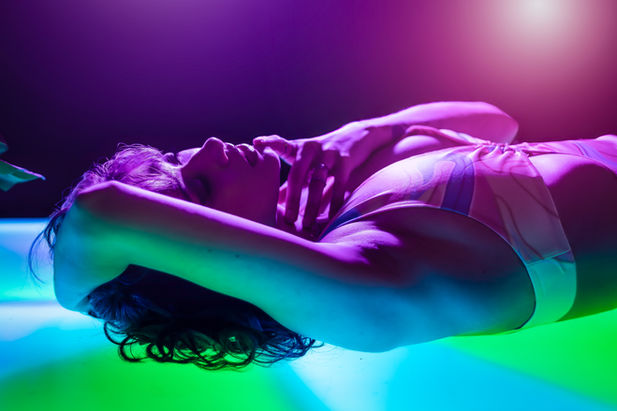 woman laying on light up floor with pink and purple lights on her