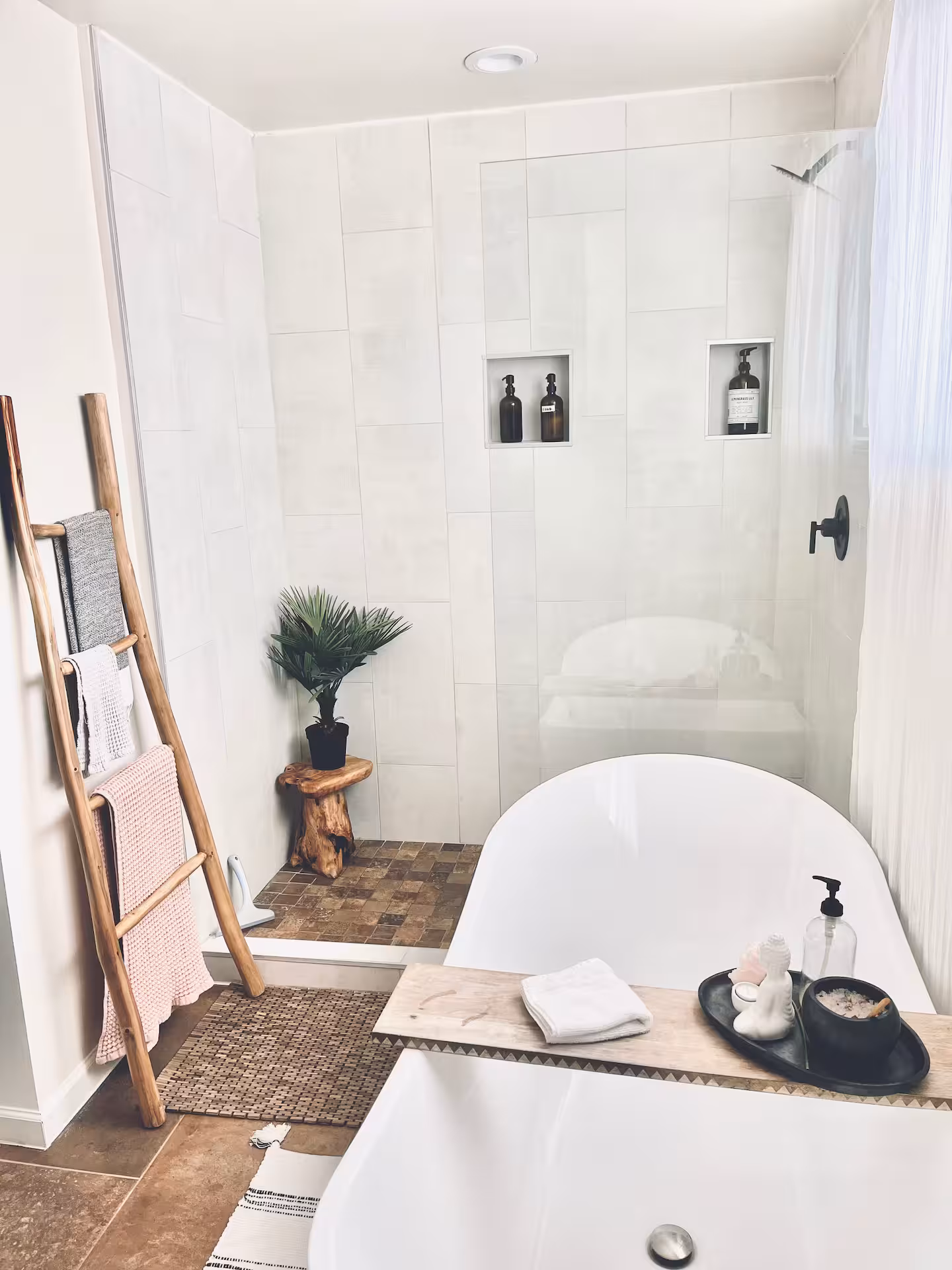 A modern white freestanding bathtub with elegant gold fixtures, natural lighting, and a tray with greenery and décor, offering a serene setting for boudoir photography
