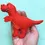 Thumbnail: Side view of a red felt T.Rex dinosaur held on a hand