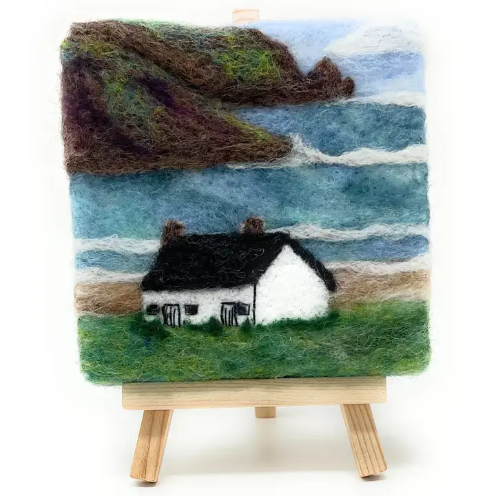 2d needle felted picture of a little white Bothy by the seashore