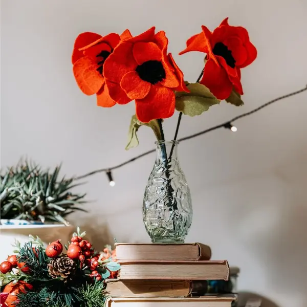 Thumbnail: Finished red felt poppies in a glass jar standing on some books