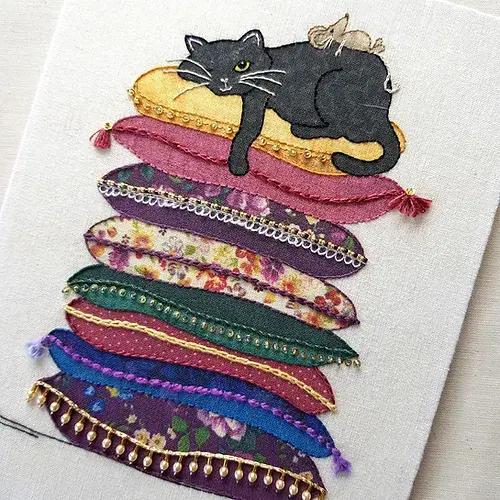 Black cat laying on a pile of assorted patterned and decorated pillows