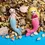 Thumbnail: Front view of male and female mermaids lying on a beach of stones and shells