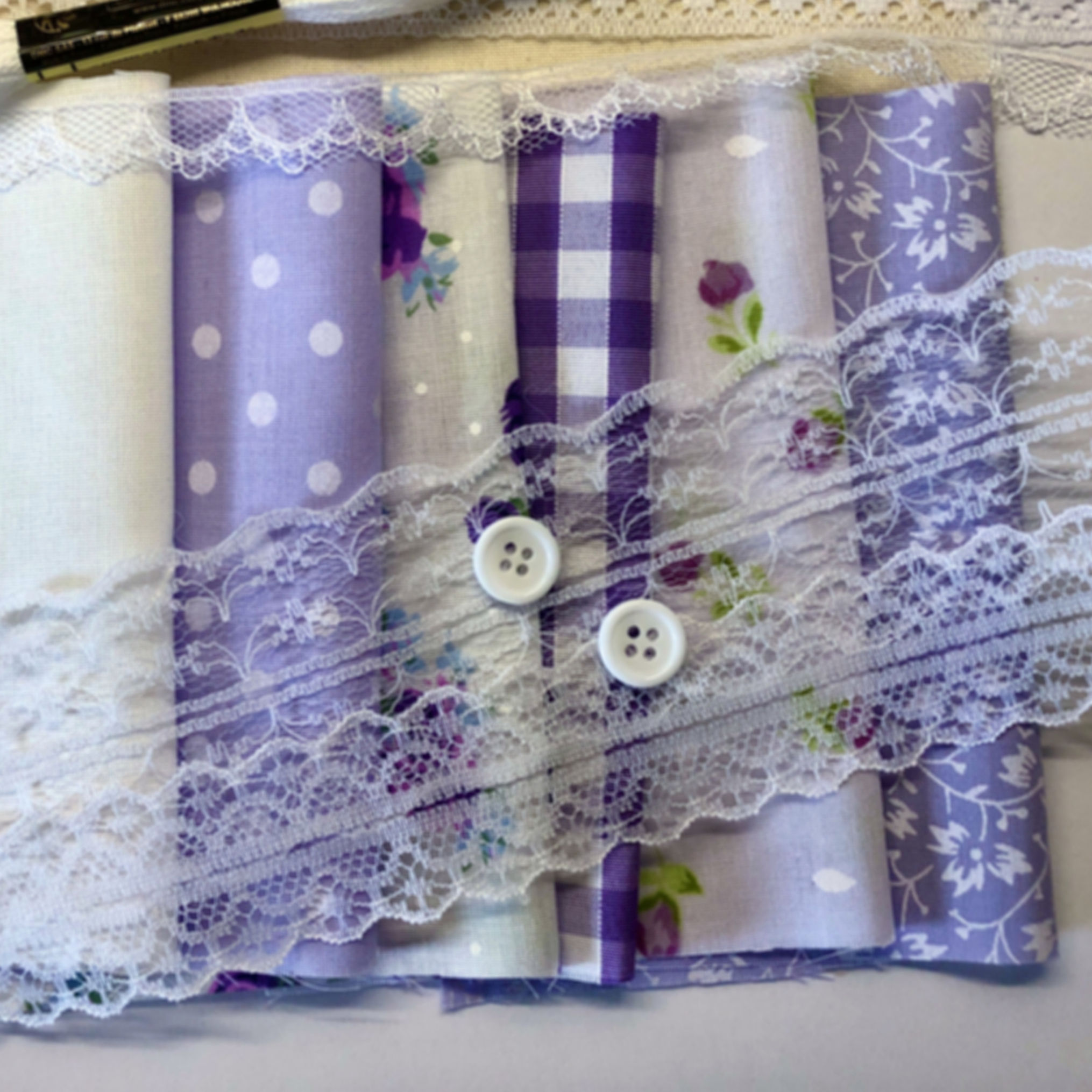 Collection of material in purples, lace of different kings and some white buttons