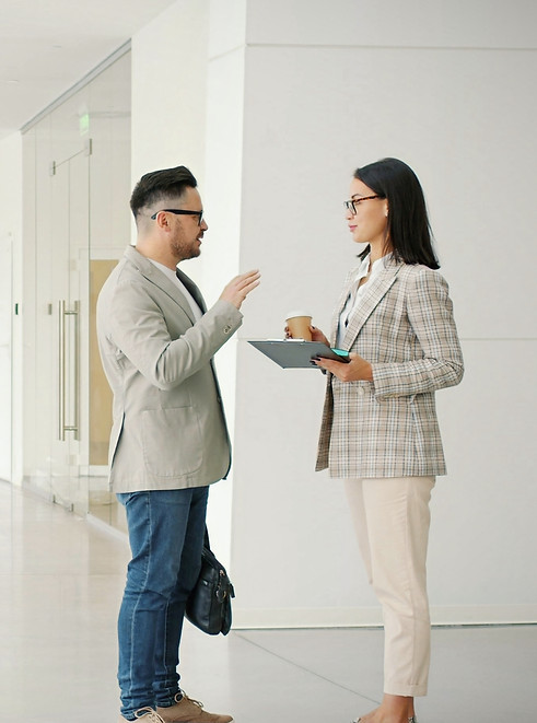 Businesspeople men ad women are talking and walking indoors in light office building corri