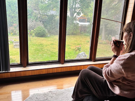 Alex boit une tasse de thé devant une grande fenêtre en automne, article sur l'ostéoporose et la maladie cœliaque à la ménopause