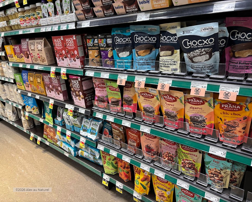 Rayon sans gluten d'une épicerie au Québec avec une large sélection de produits certifiés : barres et biscuits MadeGood, chocolats ChocXo, mélanges de noix et snacks biologiques Prana, clusters Kind et fèves edamame Gimme — étiquettes sans gluten bien visibles sur les tablettes.