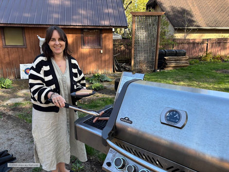 Alex au Naturel souriante devant son BBQ Napoleon dans son jardin, tenant des pinces de cuisine — illustration de la maladie cœliaque et du barbecue en été au Québec, profiter des grillades sans contamination croisée.