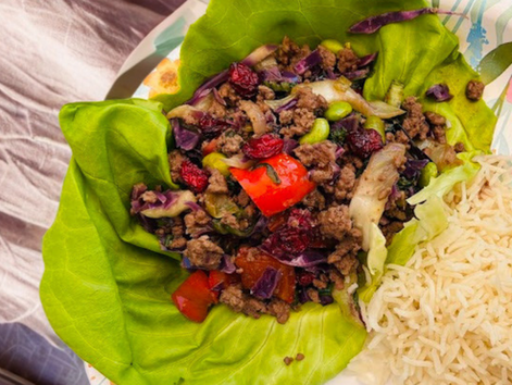Wraps de laitue au bœuf épicé, sirop d'érable et canneberges séchées, servis avec du riz dans une assiette fleurie