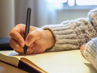 Woman in jumper writing in a notebook