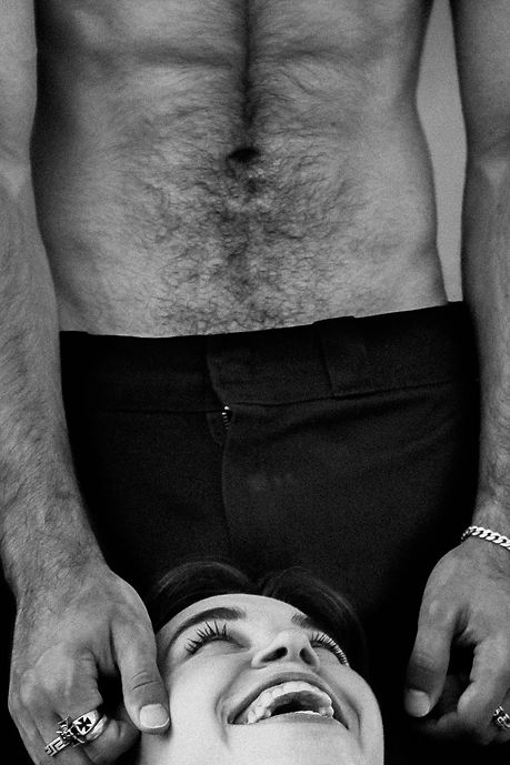 a woman smiling up at a muscular shirtless man who is caressing her face