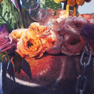 Close-up of a floral arrangement with peach and lavender roses, craspedia, and transparent glass spheres set in a textured concrete base, part of Urku Expressions' Concept Summer campaign.