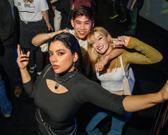 A woman and a couple are posing for the camera in a nightclub
