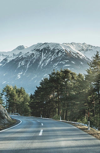 Open road veering left against a backdrop of trees and mountains
