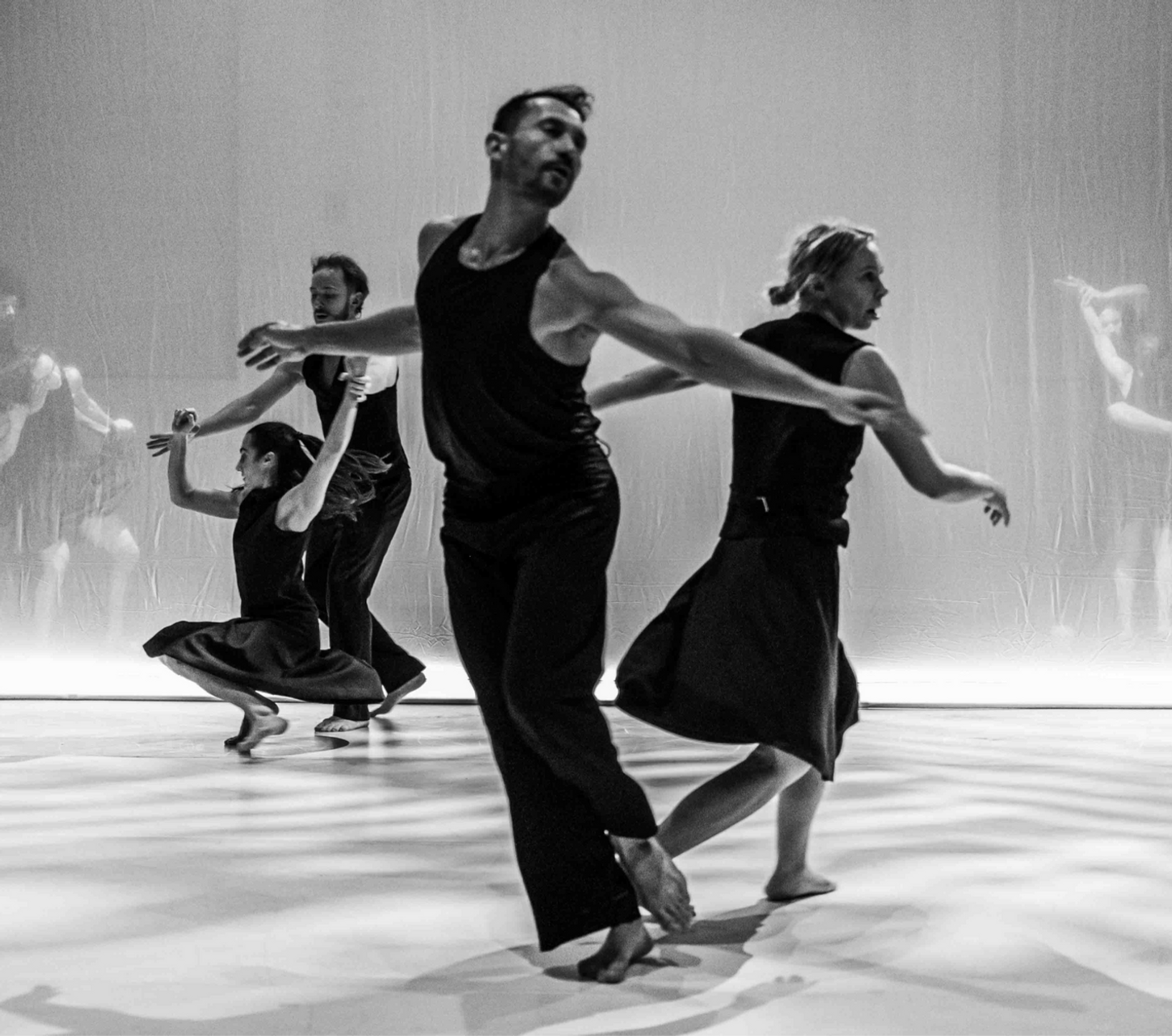 die Schwarz Weiß Tanzfotografie zeigt Tänzer vor einem durchsichtigen Vorhang
