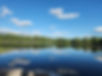 Serene lake reflecting blue sky and fluffy clouds