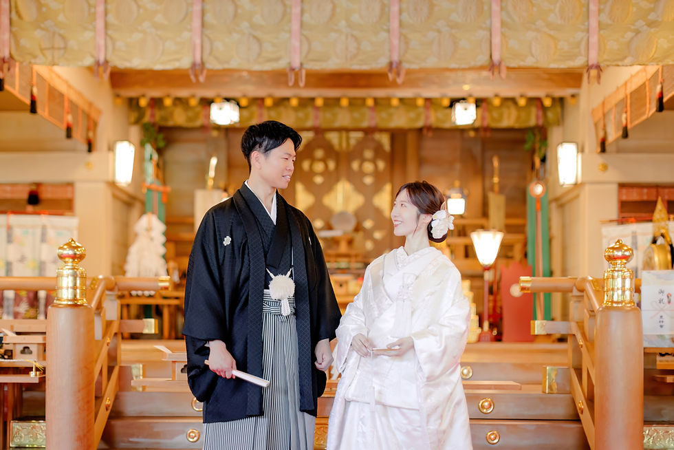 日本の神社で神前式を行う新郎新婦。白無垢や色打掛などの伝統的な婚礼衣装を着用し、プロカメラマンが挙式を撮影している様子。