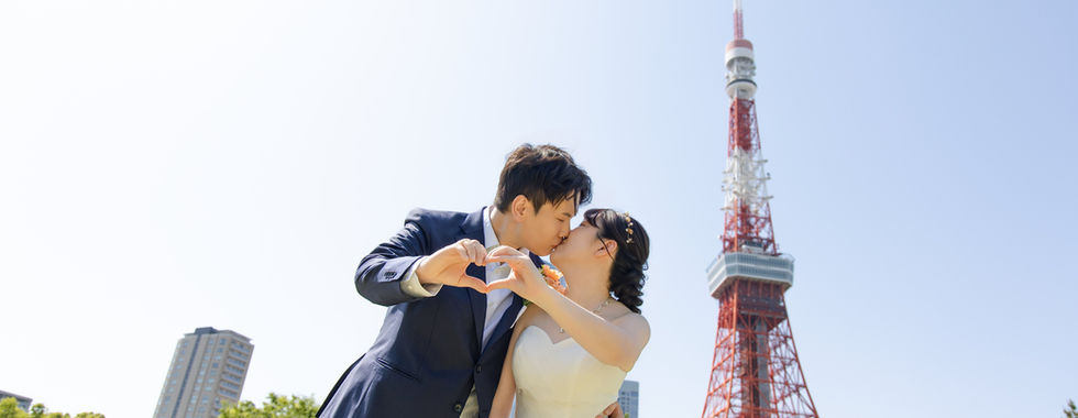 新人在東京鐵塔前比愛心姿勢拍攝甜蜜婚紗照。