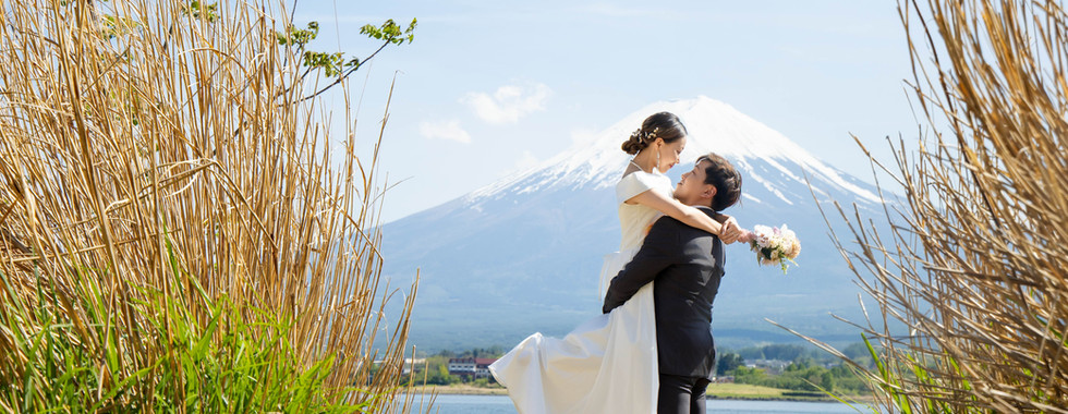 groom lifting bride beside lake with mount fuji view