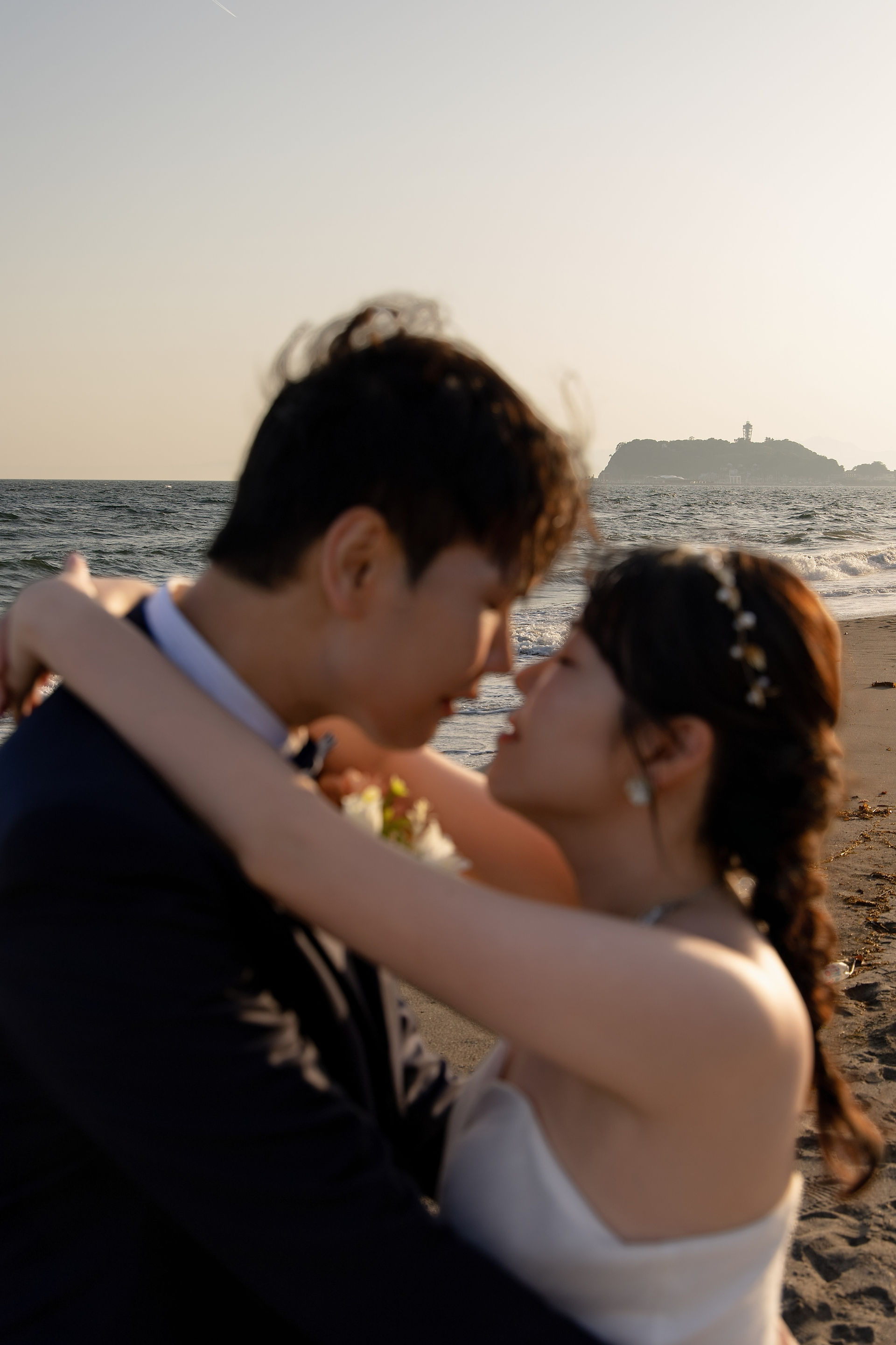 Close-up portrait of a bride and groom embracing on Shichirigahama Beach during a romantic Kamakura pre-wedding photoshoot.