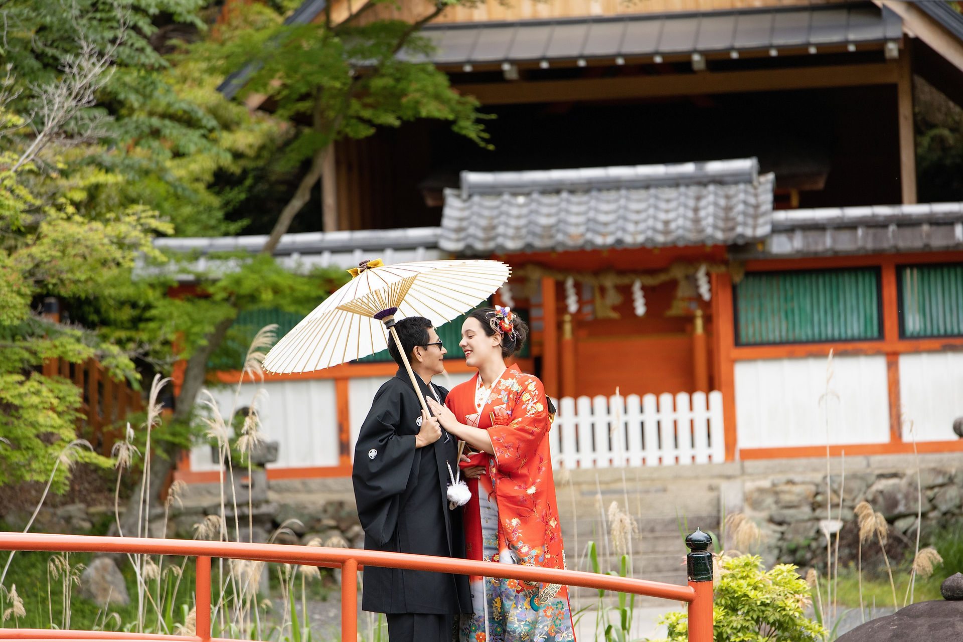 Traditional Japanese wedding portrait surrounded by red autumn foliage at a Kyoto shrine.