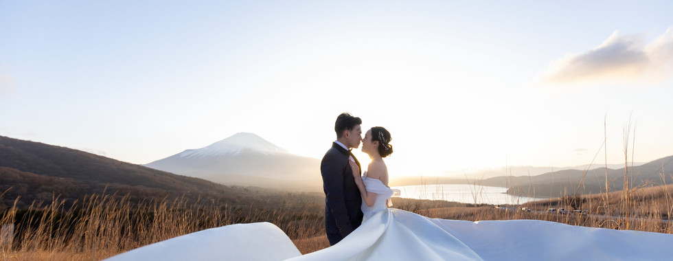 Couple embracing on a panoramic viewpoint overlooking Mount Fuji during sunset wedding photography.