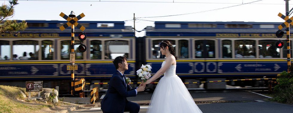 Bride and groom walking on a coastal road overlooking the sea near the Enoden railway in Kamakura, Japan.