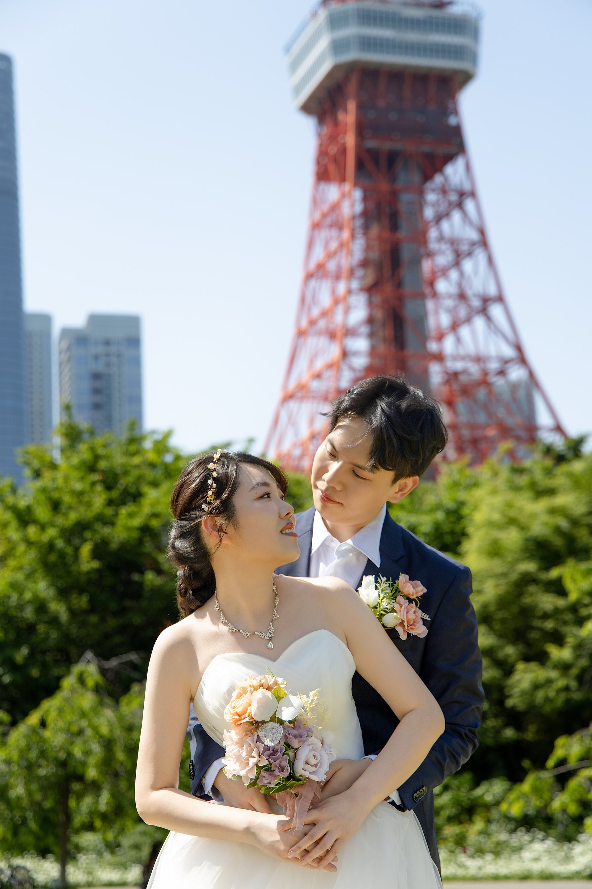 Bride and groom posing beneath Tokyo Tower in Shiba Park during a Tokyo pre-wedding photoshoot.