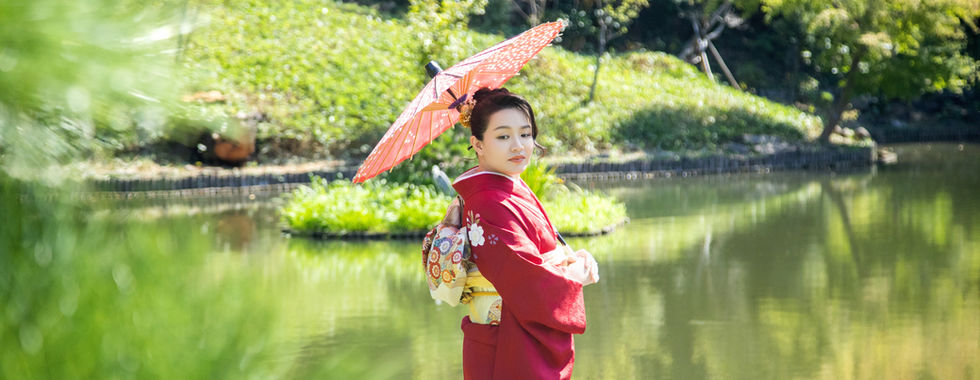 新娘穿著和服手持紅色和傘在池塘旁拍攝肖像。