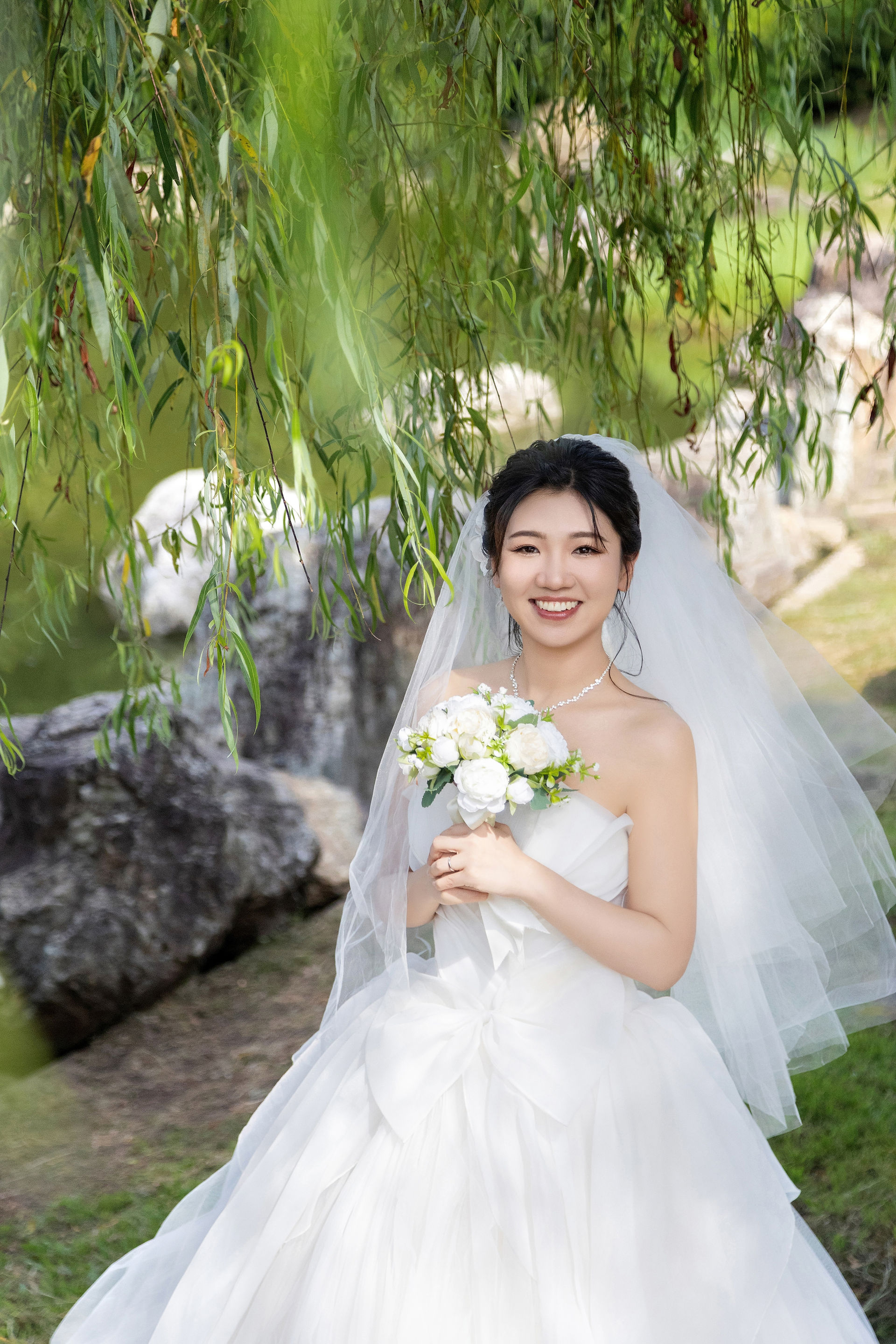 bridal portrait beside willow trees in kasai rinkai park