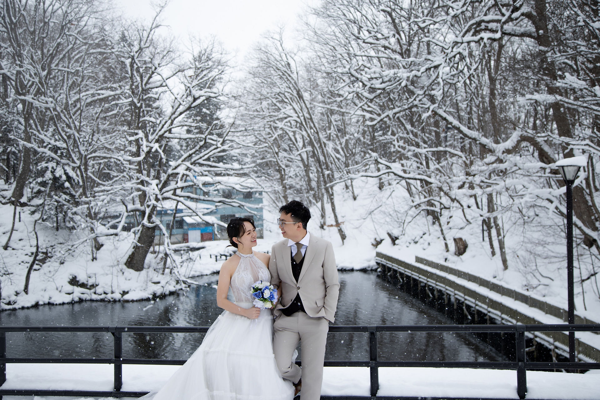 北海道の小樽運河で雪の中で抱き合う新郎新婦のロマンチックな写真｜海外カップル