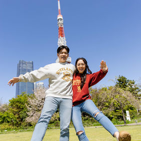 joyful couple portrait beneath tokyo tower blue sky